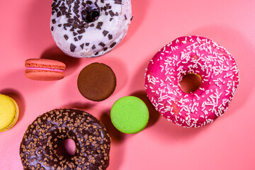 Fresh glazed donuts and french macaroons isolated on a pink background