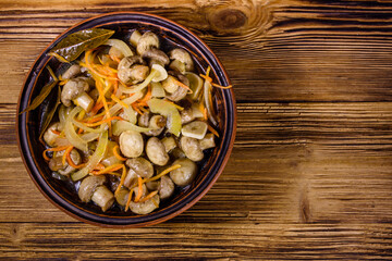 Canned mushrooms with carrot and onion in a ceramic bowl. Top view