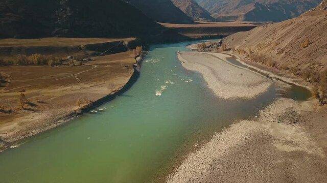 Altai Republic, Siberia, Russia. The two rivers Biya and Katun join into one river. Landscape with autumn wildlife: huge mountains, stone coast, yellow trees with golden foliage, green turquoise river