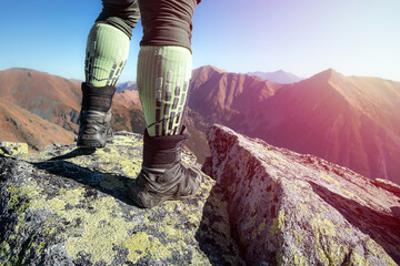 Hiker legs in worn high boots on the rocks in the high mountains. 