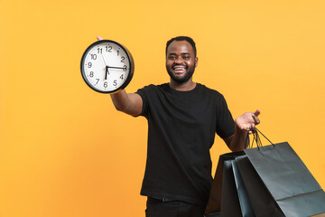 Black man laughing while showing clock and shopping bags