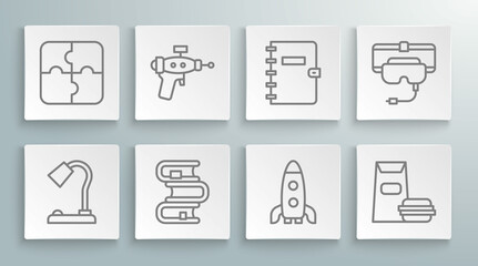 Set line Table lamp, Ray gun, Book, Rocket ship, Burger, Spiral notebook, Virtual reality glasses and Piece of puzzle icon. Vector