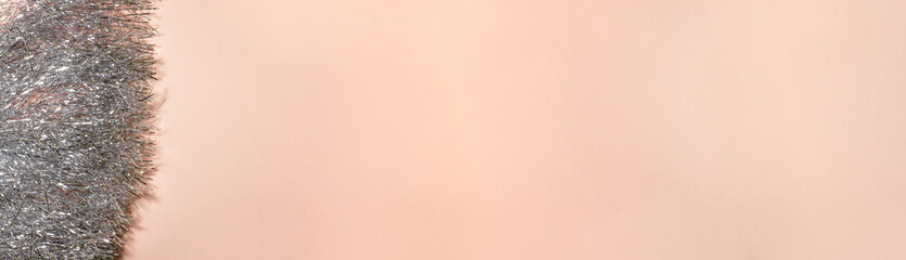 Banner of silver shiny bright garland on beige background on the left. Holidays greeting cards and Christmas template concept with copy space.