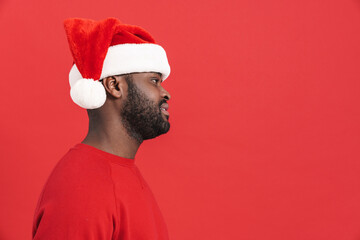 Black man wearing christmas hat smiling and looking aside