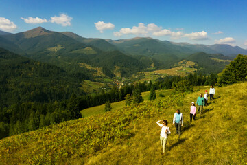 Fototapeta na wymiar Group of tourists walking on hill in mountains. Drone photography