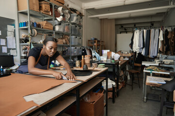African female artisan cutting leather at a workshop bench