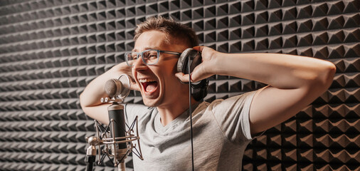 The vocalist sings in the studio in a microphone. Man in headphones writes a podcast, an audiobook....