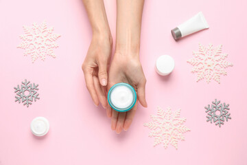 Woman with jar of hand cream at pink background, top view