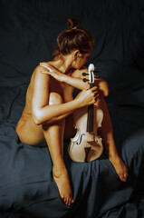 Beautiful naked girl on a noble background with a white violin in her hands  © Ruslan Sikunov