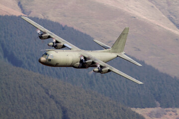 Lockheed C130 Hercules transport aeroplane flying low level in the United Kingdom. Green C-130 - obrazy, fototapety, plakaty
