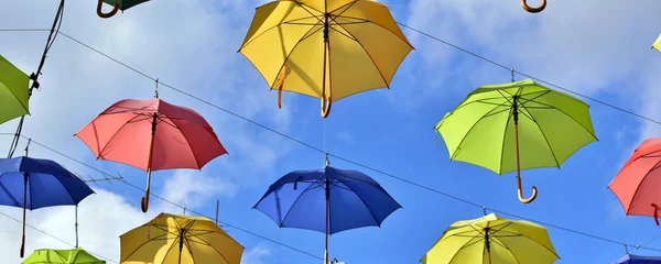 Fotobehang Colorful umbrella in autumn. Hanging umbrellas of different colors on  background of blue sky © Irik