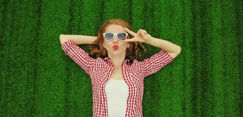 Portrait of young relaxing woman lying on the grass background in park