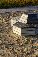 Close up of grey wood planks construction for sitting. Empty modern wooden bench. Wet sand around. Wooden walkway on the back. Reidi street, Tallinn, Estonia