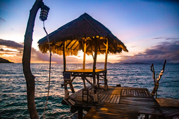 Sunset over wooden beach bar in sea and hut on pier in koh Mak island, Trat, Thailand