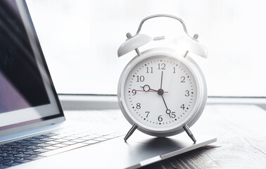 Work time concept. Home desktop with laptop and alarm clock on desk