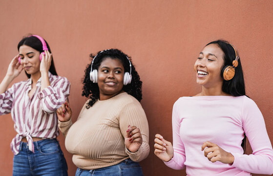 Young latin women dancing to music playlist with wireless headphone