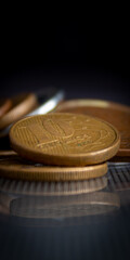 moedas empilhadas em superf&iacute;cie de vidro, refletindo no vidro, em um fundo escuro, com o foco em uma moeda de 10 centavos de BRL. 