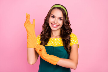 Photo of dreamy sweet young lady dressed green apron orange gloves ready cleaning smiling isolated pink color background