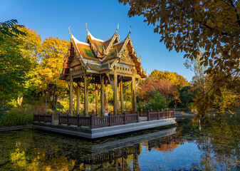 Thailändische Sala, Tempel mit Buddha Statue im Westpark, München - farbemfrohe herbstliche Bäume und Spiegelung im See