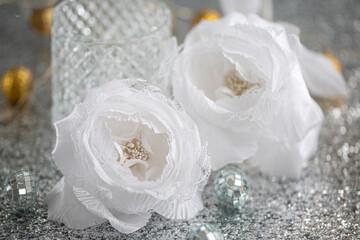 Silk white roses with lace and blurred light background with bokeh. Christmas decoration to decorate the festive table.