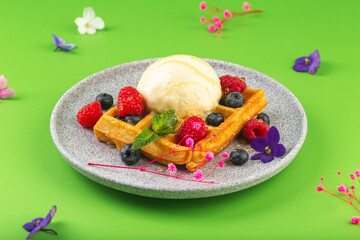 Belgian waffles with ice cream berries and flower on green