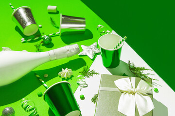 Christmas composition made of present box, paper glasses with straws, white champagne bottle, meringues and green baubles. Festive and party concept. 2022 new year background.