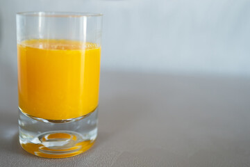 A glass of orange juce on the grey background