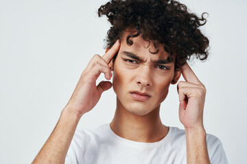 guy with curly hair in a white t-shirt headache migraine discontent