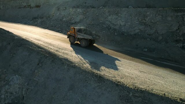 Career dump truck goes in a gold mine. Aerial view of large mining trucks on a gold mine. Open pit mine quarrying extractive industry stripping work.