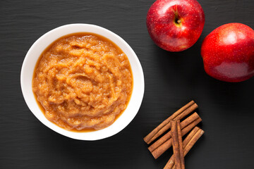 Homemade Raw Apple Sauce in a White Bowl on a black surface, top view. From above, flat lay, overhead.