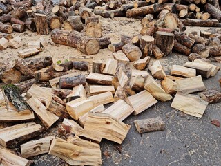 Stack of firewood in winter. Pile of wood logs from trunk of old trees in the yard of residential house. Preparation of people to winter frost at home. Scenic view in the courtyard of building.
