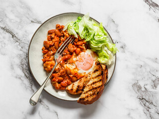 Baked shakshuka with tomato sauce beans and iceberg salad is a delicious healthy breakfast on a light background. top view