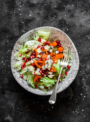 Delicious seasonal salad with pumpkin, gorgonzola, pomegranate, iceberg on a dark background, top view