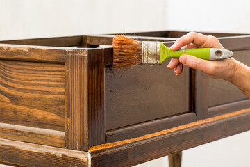 Con un pincel en la mano, barnizando un mueble de madera antiguo