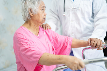 Fototapeta premium Asian nurse physiotherapist doctor care, help and support senior or elderly old lady woman patient walk with walker at hospital ward, healthy strong medical concept.