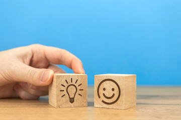 Business creative idea concept. Hand with light bulb icon on a wooden cube and smiley face of leadership person. Copy space photo