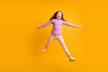 Fototapeta na wymiar Full size photo of happy good mood excited energetic little girl jumping having fun isolated on yellow color background