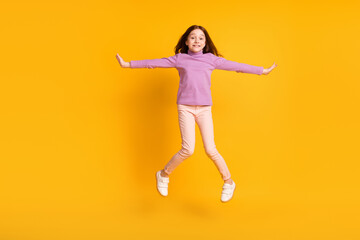Fototapeta na wymiar Full size photo of beautiful happy positive energetic little girl jumping having fun isolated on yellow color background