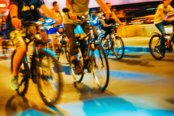 Close-up of blurred silhouette of riding cyclists on city roadway, night, abstract, motion blur