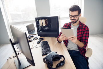 Portrait of attractive trendy focused cheerful smart guy reading tech report creating program at...