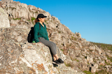 young woman on top of a mountain appreciating the landscape on a sunny day relaxed with her...