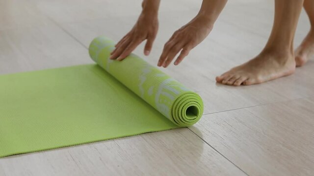 Woman rolls upa rug of yoga in yoga class room, yoga time end, yoga class