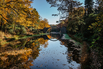 Unique looking bridge Rakotzbrucke,also called Devils Bridge,Saxony,Germany.Built to create circle when it is reflected in waters.Colorful fall landscape.Fantastic autumn foliage.Amazing place