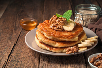 Pancakes with a nut and a banana close-up on a wooden background.