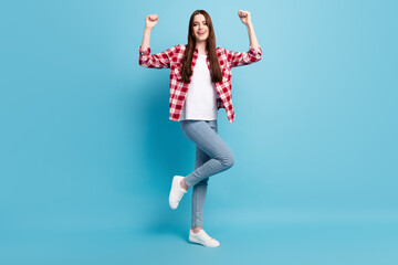 Full body photo of astonished millennial brunette lady fists up wear red shirt jeans isolated on blue color background
