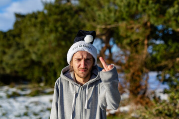 A grumpy young man wearing a black santa hat with the words Bah Humbug written on it