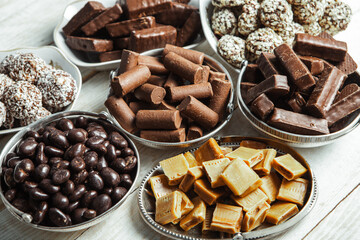 Assorted chocolate candies on wooden background. Chocolate sweets. Dessert background.