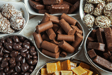 Assorted chocolate candies on wooden background. Chocolate sweets. Dessert background.