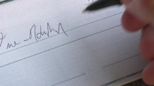 A panning closeup of writing a check.