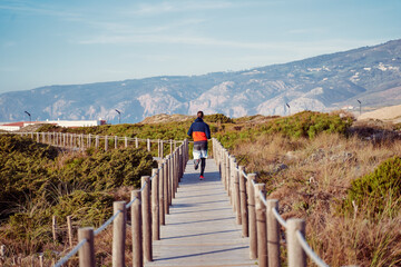 Sports lifestyle. Man running on wooden pedestrian walkway through Sintra-Cascais natural park.